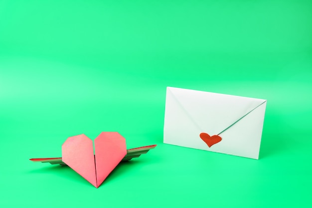 White envelope with red heart and red origami paper heart