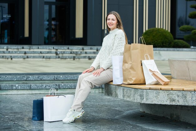Photo white european lady comes out of the shopping center with full bags