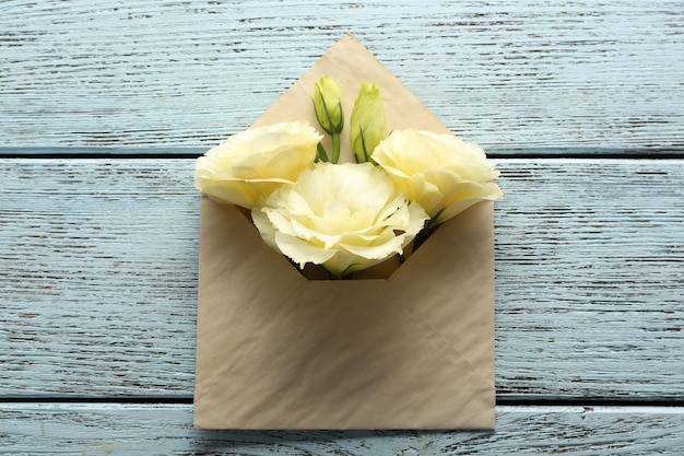 White eustoma in envelope on wooden background