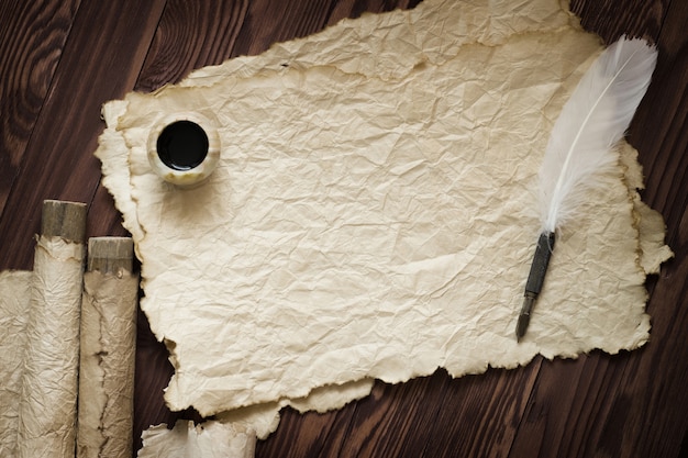 Photo white feather and ancient scroll on brown plank