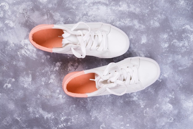 White female sneakers on stone background. Flat lay, top view minimal background. 