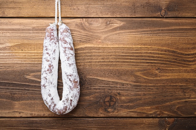 White fermented fuet sausage on light wood table, flat lay with copy space