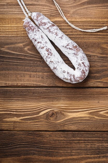 White fermented fuet sausage on wood table with space for\
text.