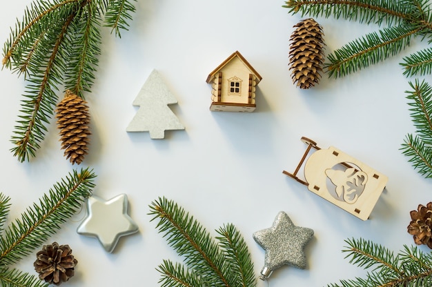 White festive background with spruce branches, cones, silver stars and wooden toys. top view.