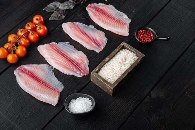 Photo white fish fillet, with basmati rice and cherry tomatoes ingredients, on black wooden table with copy space for text