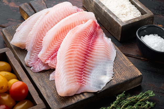 White fish fillet, with basmati rice and cherry tomatoes ingredients, on old wooden table