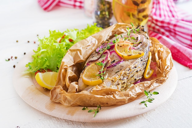 Стейк из белой рыбы (карп), запеченный в пергаментной бумаге с овощами. Рыбное блюдо.