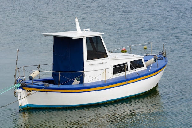 Белая рыбацкая моторная лодка на якоре в море