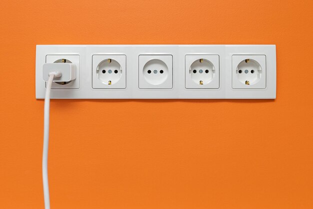 白い壁に置かれた白い5道の壁電源ソケット