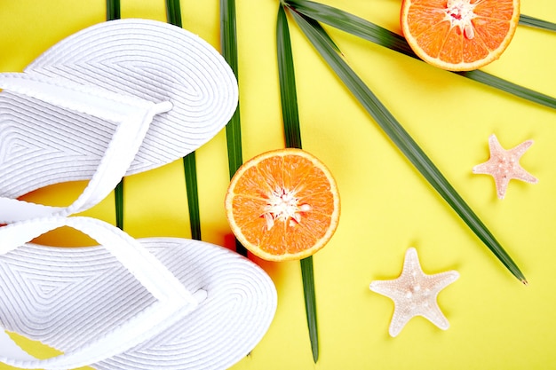 Photo white flip flops, orange fruit, starfish and palm