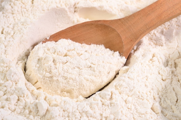 White flour in a wooden spoon close up