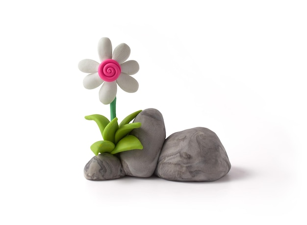White flower and fuchsia center on cracked textured stones and grass made from plasticine