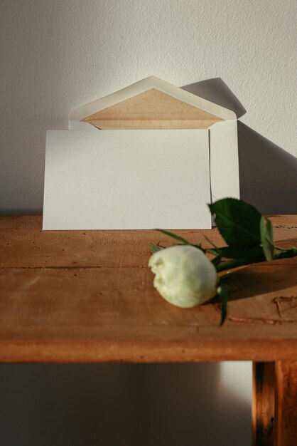 a white flower is on a wooden table with a piece of paper on it