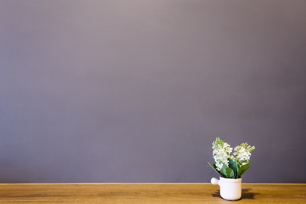 Photo white flower vase put on the table with brick wall interior room.