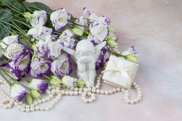 Коробка белых цветов с подарочной фигуркой ангела и жемчугом