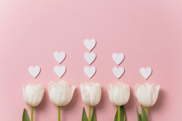 White flowers and hearts on a pastel pink background