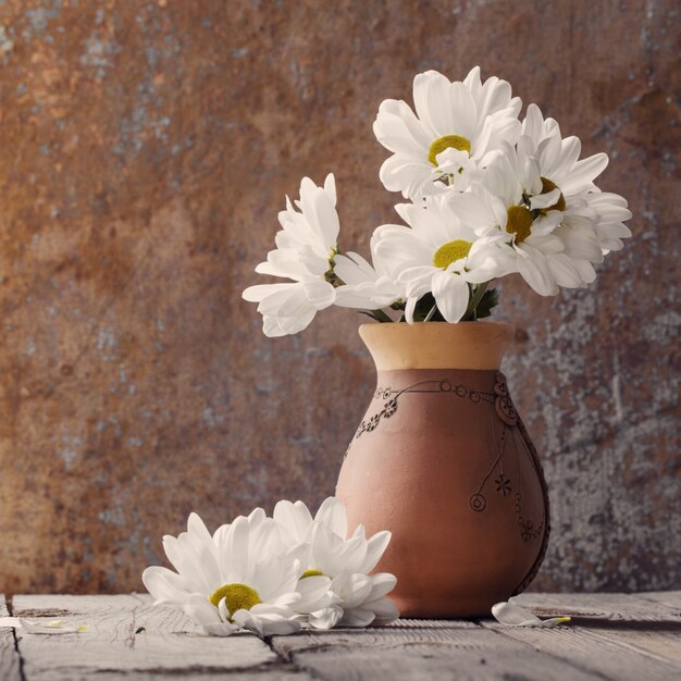 White flowers in jug on old wooden painted table