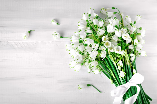 White flowers of Loddon Lily lie on white wooden boards.