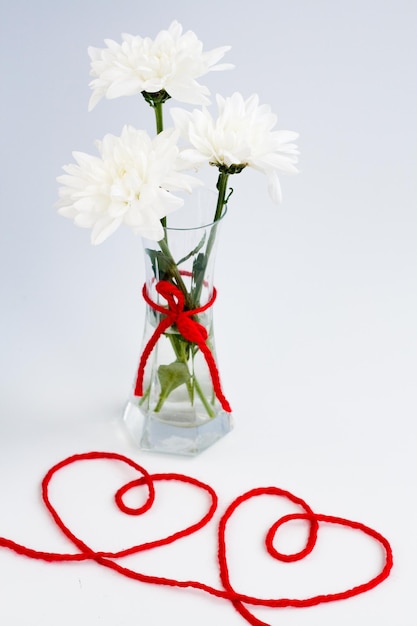 White flowers in a small glass vase with a red bow