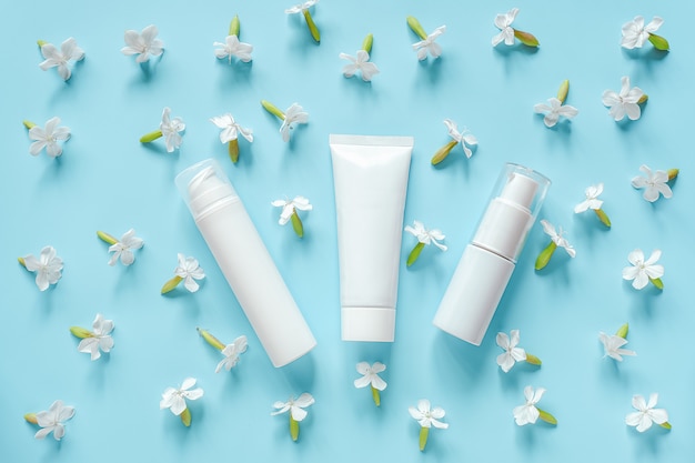 Photo white flowers and three cosmetic tube, bottle for cream, ointment, toothpaste. natural organic cosmetics