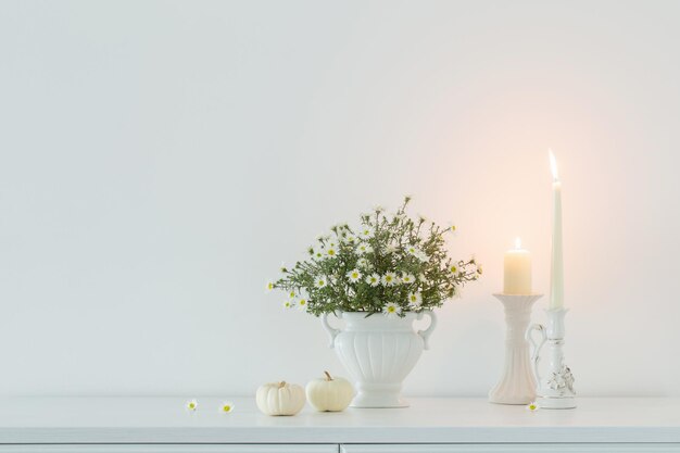 White flowers in white ceramic vase in white interior