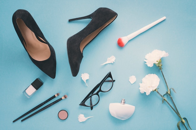 Photo white flowers with cosmetics and woman shoes on blue table