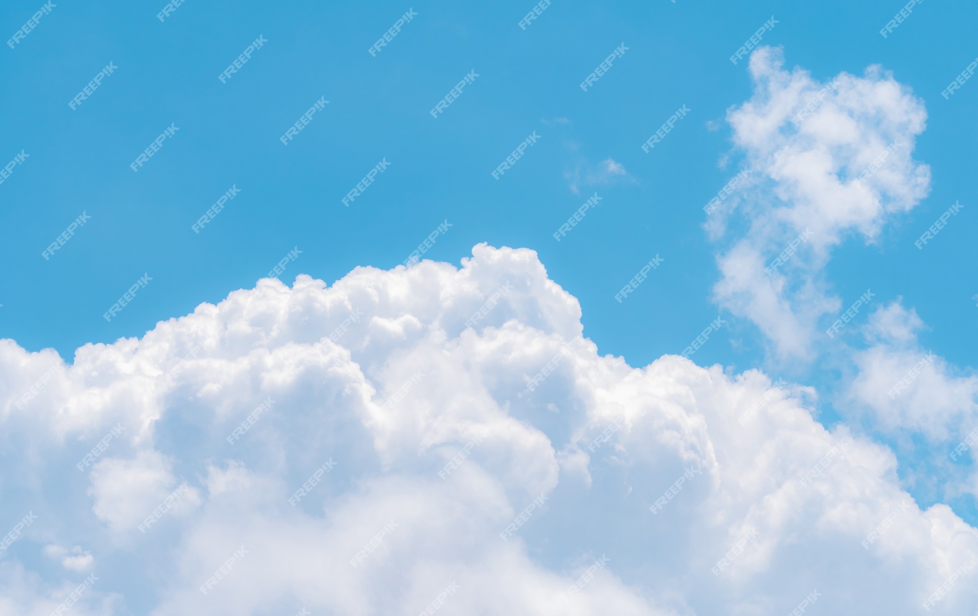 Cute puffy small white clouds on a sunny aqua blue sky Water