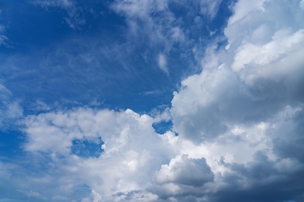 白いふわふわの雲が黒い背景と青い空に立っています