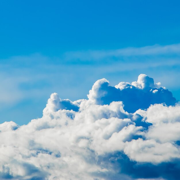 White fluffy cumulus clouds on the blue sky in the sunshine.