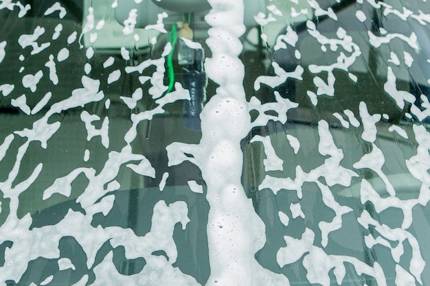 White foam and soap on dark background. Abstract pattern. The concept of washing oily pan or black car