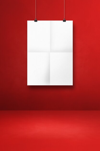 White folded poster hanging on a red wall with clips. Blank mockup template