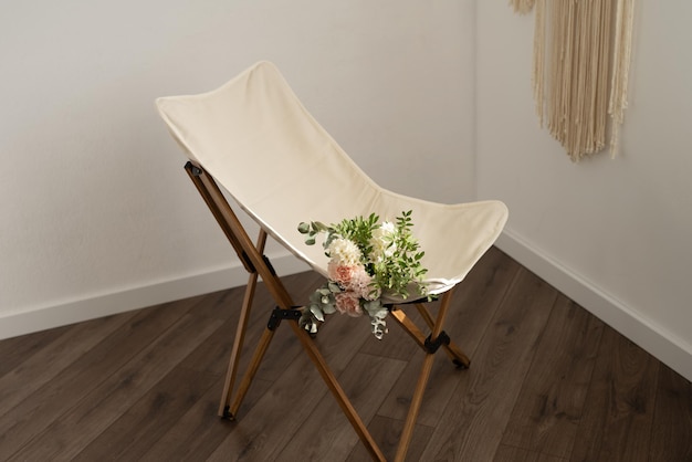White folding chair with a bouquet of flowers on a wooden floor