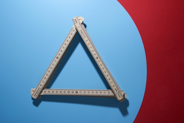 White folding ruler in triangle shape isolated over a blue and red background