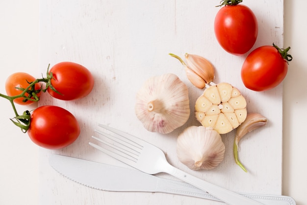 White fork knife plate on an old wooden plank tray and tomatoes