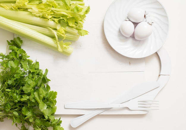 White fork knife plate on an old wooden plank tray with vegetables