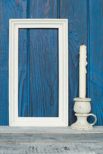 White frame and a candle on a background of blue boards