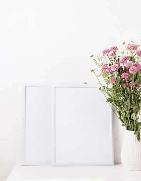 White frame mockup with chrysanthemum flowers in a vase on a white table