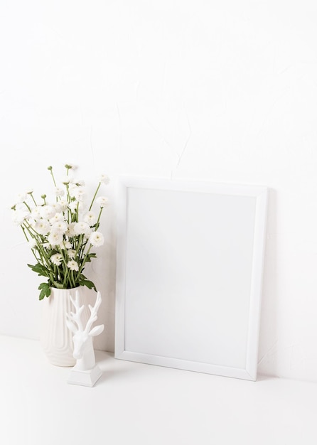 Макет белой рамки с цветами хризантемы в вазе на белом столе