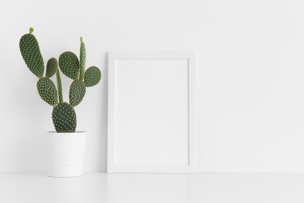 Photo white frame mockup with a opuntia cactus in a pot on a white table portrait orientation