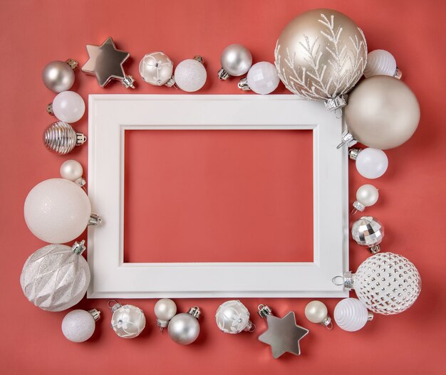 ピンクの背景のモックアップに銀と白のクリスマスの装飾で囲まれた白いフレーム