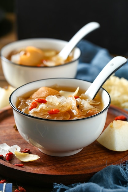 Foto zuppa di funghi bianchi e pera in ciotola bianca su piatto di legno