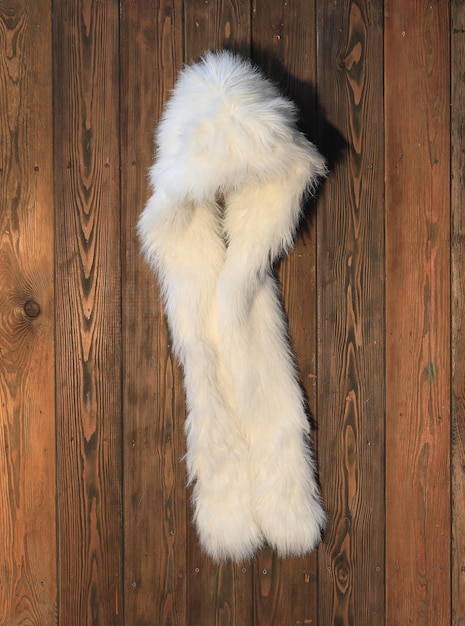 Photo white fur hat on a hanger on a wooden wall