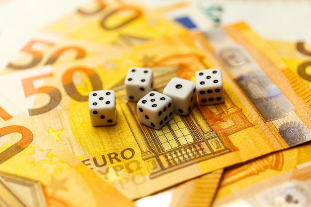 White gaming dice and money on dark table