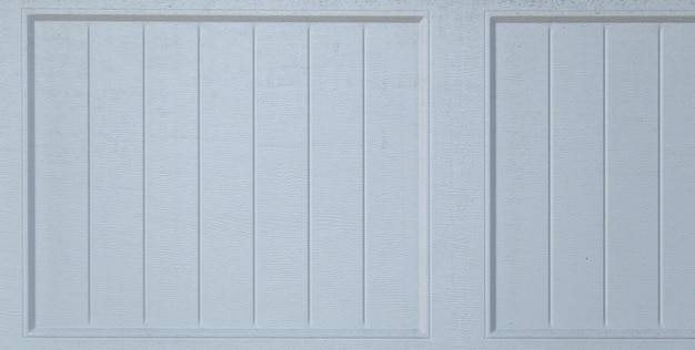 Белая дверь гаража с окрашенной в белый цвет деревянной панелью.