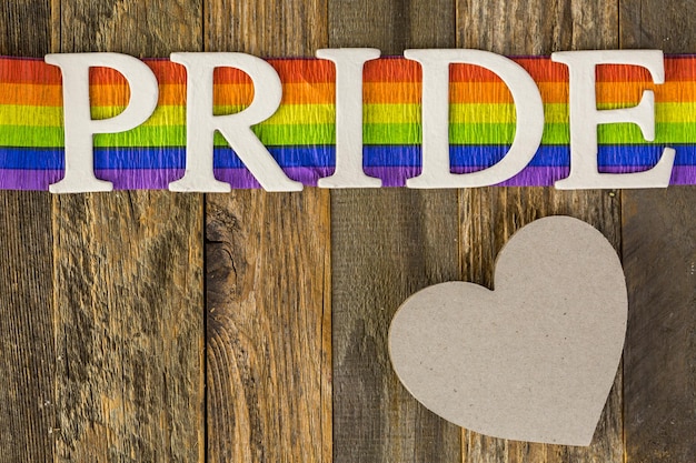 White Gay Pride sign on wood background.