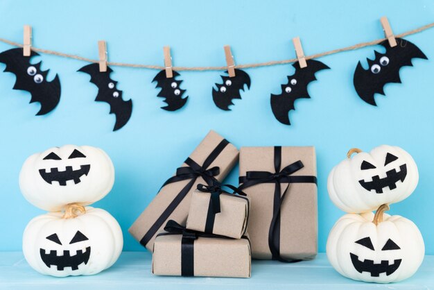 White ghost pumpkin with gift box and bat on sky blue background