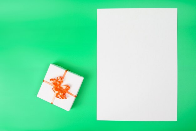 White gift box on green surface and blank card