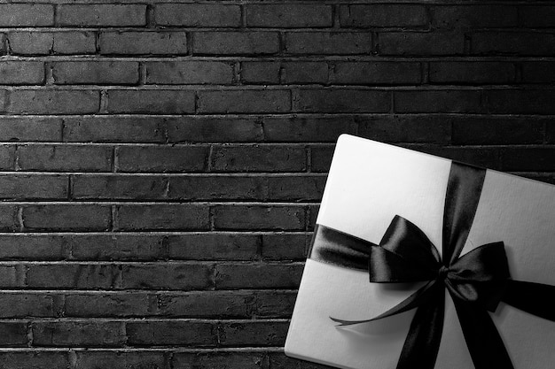 검은색 벽 배경이 있는 검은색 리본이 있는 흰색 선물 상자. 블랙 프라이데이 컨셉