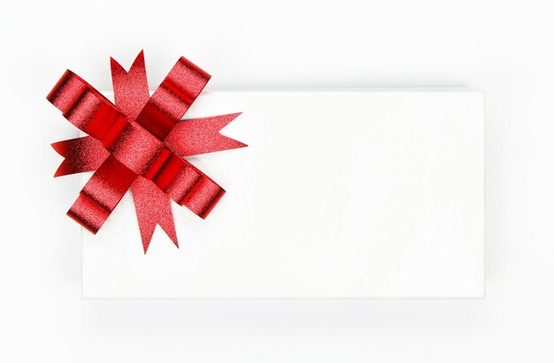 White gift box with red ribbon and bow isolated on white background