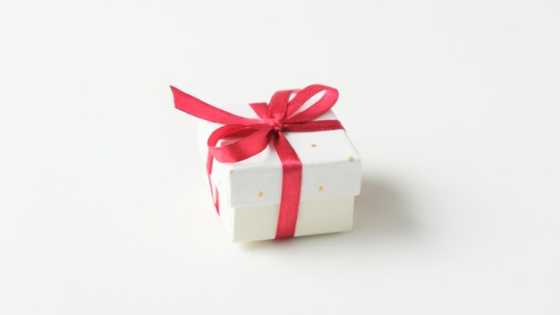 white gift box with red ribbon bow, on white